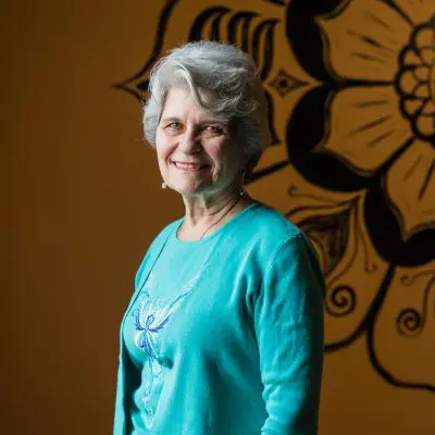 A woman standing in front of a wall with flowers.